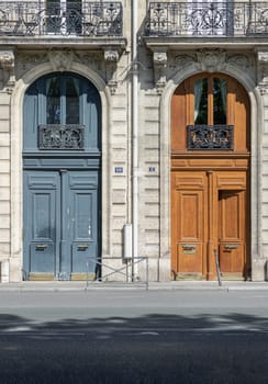 France, Paris - May 03, 2025 - Magnificent entrance facade doors of Ancient building in Paris. Architectural splendour details of wooden front doors with glass windows and wrought iron steel balcony, use it as your Wallpaper, Poster and Space for text, Selective focus.