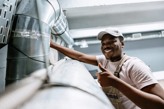 A cheerful technician adjusts a section of the ventilation system in a well-lit industrial area.