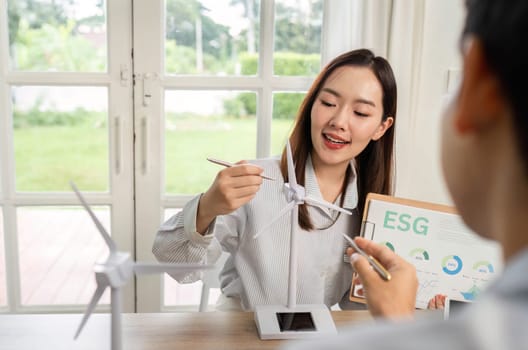 Two professionals engage in a discussion about ESG strategies, showcasing renewable energy models and data insights.