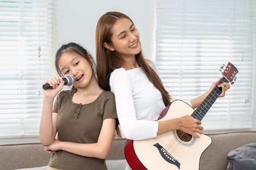 A mother and her daughter share a musical duet, creating a joyful atmosphere filled with laughter and love, celebrating their bond.
