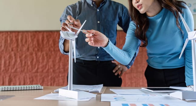 A woman and a man collaborate on a wind energy project, discussing model details and innovative solutions.