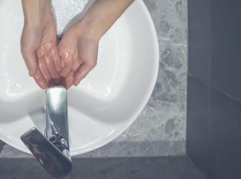 A girl washes her hands with soap under a stream of water close-up, a woman takes care of hygiene, cleanliness, disinfection.