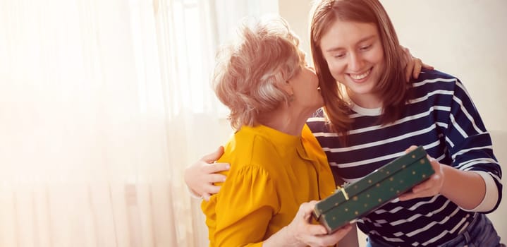 Two women, relatives, happily spend time together, grandmother and daughter give gifts to each other for the holidays, make pleasant surprises, love and emotional bonding inside the family.