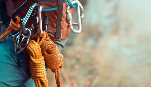 Climbing equipment, ropes, carabiners, harness, belay, close-up of a rock-climber put on by a girl, the traveler leads an active lifestyle and is engaged in mountaineering.