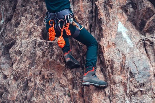 Climbing equipment, ropes, carabiners, harness, belay, close-up of a rock-climber put on by a girl, the traveler leads an active lifestyle and is engaged in mountaineering.