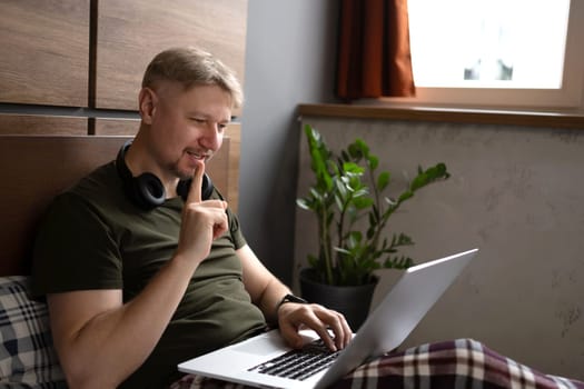 Man Lying In Bed With A Laptop At Home In The Morning