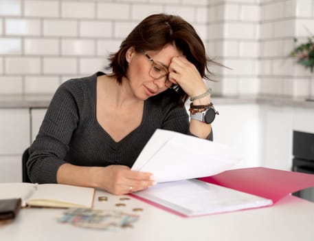 Distressed Woman Sorts Out Finances At Home Table