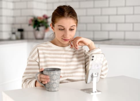 Unhappy Teen Girl Looking At Smartphone At Home
