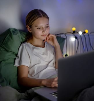 Cute Little Girl In Bed Watching An Interesting Movie On Laptop Before Sleep
