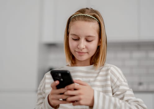 Cute Little Girl At Home Using A Smartphone, Scrolling Through Social Media Feed