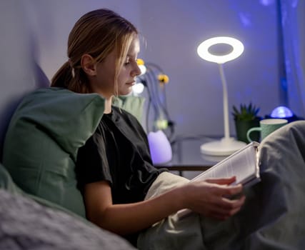 Cute Little Girl Reading A Book As Homework In Bed Before Sleep In A Cozy Kids Room