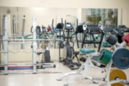 Interior Of The Modern Gym, With Machines And Weights, Blurred And Out Of Focus