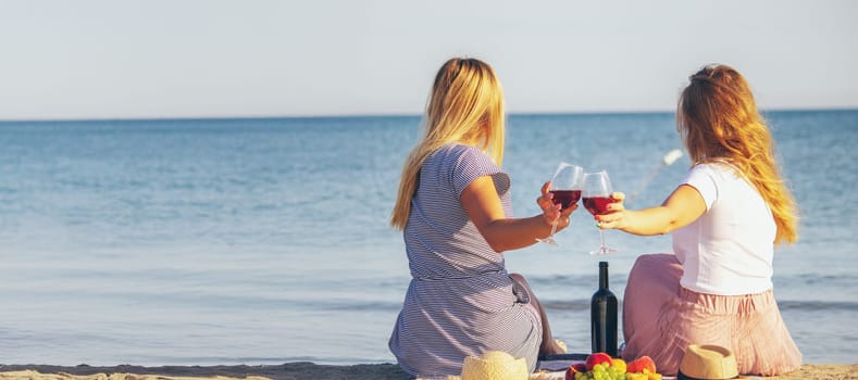 Two girls drinking wine by the sea.