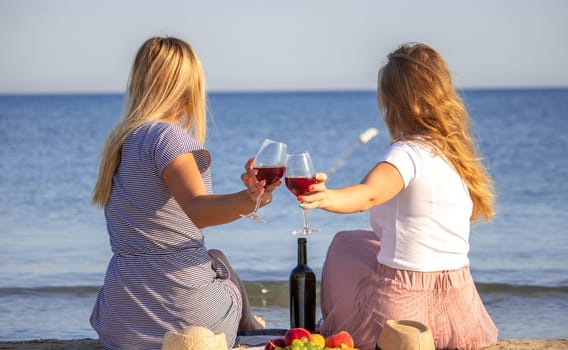 Two girls drinking wine by the sea.