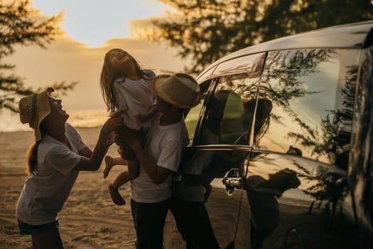 Asian family playing near car window at sunset feeling funny in holidays and relaxation together. Happy weekend travel enjoy summer at beach. summer vacation travel driving road trip concept