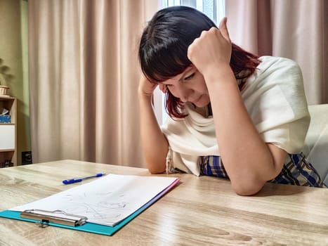 Middle-aged woman psychologist sits in her office with a thoughtful expression, reflecting on client notes and ideas during a session.