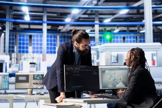 Programmer in photovoltaics factory updates software of assembly lines machinery, communicating changes to manager. Engineer informing supervisor of code changes in solar panels plant software