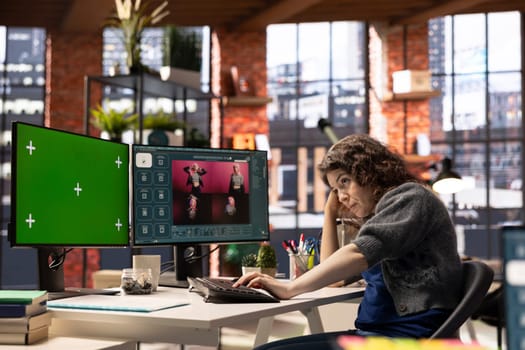 Focused woman using AI chatbot software and copy space display, turning text prompt into photos for a creative project. Young photographer uses text to image generative models on PC.