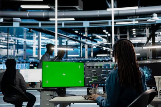 IT specialist in server hub using mockup PC to fix errors slowing down hardware. System administrator in data center using isolated screen computer to check for server performance issues