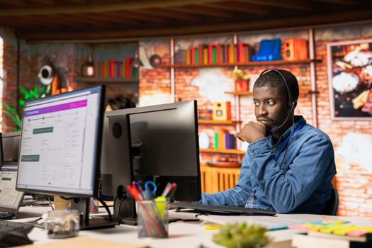Call center staff member tracking shipments in office, looking at PC screen. African american customer center employee using software to locate clients packages and provide status updates