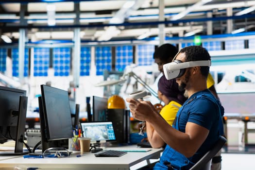 Photovoltaics facility specialist using VR tech to build models of alternative energy generators. Solar panels factory male employee building safe solar cells using virtual reality gear.