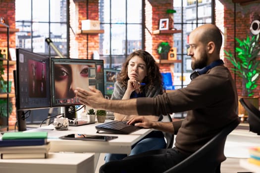 Graphic designer and photographer collaborate in a modern studio, using AI powered photo editing software on a PC. Providing automation, retouching and advanced image adjustment tools.