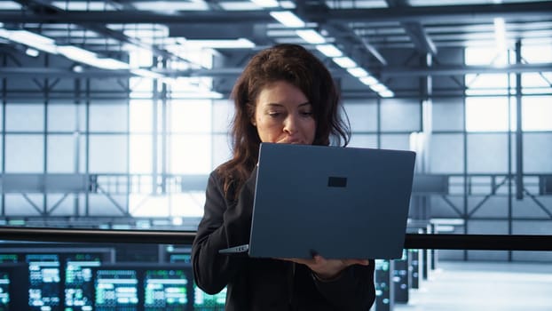 Cybersecurity expert in data center frantically trying to counter a hacker attack. Server room worker under pressure to secure sensitive information after threat alert received on laptop, camera B