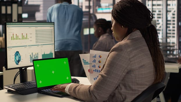 Corporate employee focused on strategic planning next to green screen on pc, accomplishing business objectives. Female consultant engaged in budget analysis and performance metrics. Camera A.