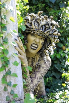 A woman dressed as Medusa with a snake's head and clawed hands
