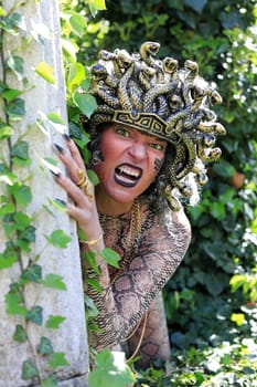 A woman dressed as Medusa with a snake's head and clawed hands