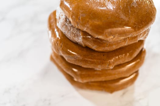 Discs of Classic Gingerbread Cookie Dough are stacked and wrapped in plastic, ready for chilling before being rolled out. Chilling helps the dough hold its shape, making it easier to cut into festive cookies.