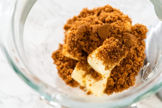 A mixing bowl filled with brown sugar and chunks of butter, ready for creaming. The mixture awaits blending to form the base of the cookie dough.