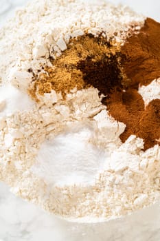 A close-up of dry ingredients for Zesty Orange Gingerbread Cookie Dough, featuring flour, cinnamon, ginger, and cloves in a glass bowl. These spices give the gingerbread its warm and aromatic profile.
