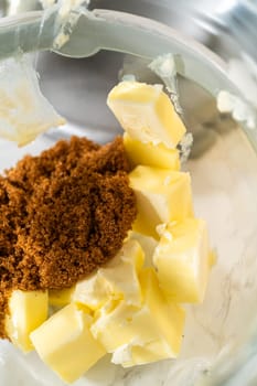 Butter and brown sugar are added to the mixing bowl, key ingredients for Chocolate Gingerbread Cookie Dough. These provide a creamy texture and deep sweetness, which complement the chocolate and spices.