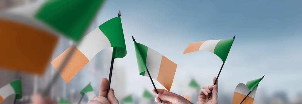 Ireland flags in their hands on a blurred urban background. The photo illustration was created without the use of artificial intelligence, only using Photoshop.