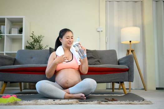 Pregnant woman taking a water break after exercising at home..