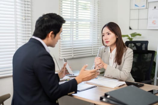 A financial advisor discusses investment strategies with a client in a modern office, focusing on financial growth and planning.