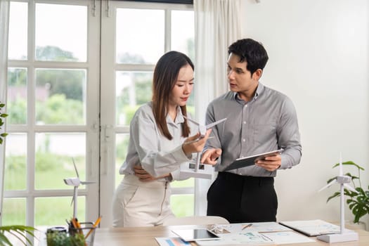 Two business professionals strategize on renewable energy projects and ESG initiatives in a bright, modern office setting.
