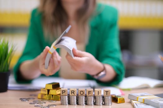 A skilled financial expert reviews records and profit statements amid shining gold bars, symbols of wealth