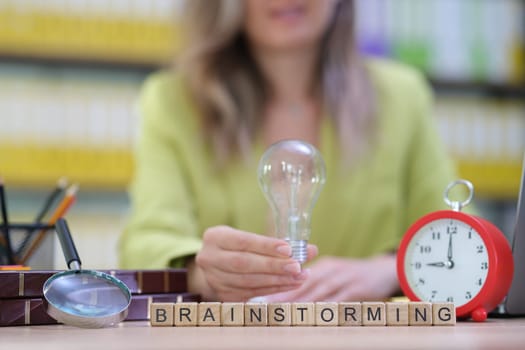 A woman who is holding a light bulb represents and symbolizes creativity within a brainstorming environment