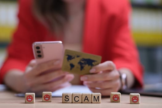 A woman is holding a phone and a credit card, underscoring the importance of being aware of digital scams