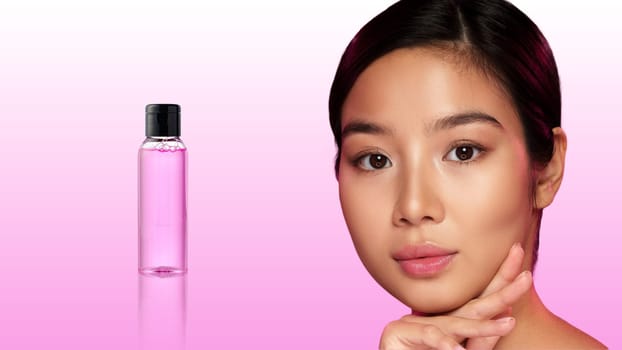 A young woman poses with confidence, highlighting a skincare product beside her. She engages the camera with a natural expression, emphasizing beauty and self-care.
