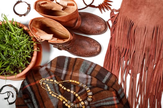 Boho Style. Leather Boots, Wooden Necklace, Denim Shorts and Hippie Bag with Fringe on White Background. Overhead View of Woman's Casual Day Outfits. Trendy Hipster Look.