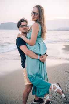 A smiling couple shares a joyful moment on the beach at sunset, with the man lifting the woman playfully near the sea waves, Alanya, Turkey