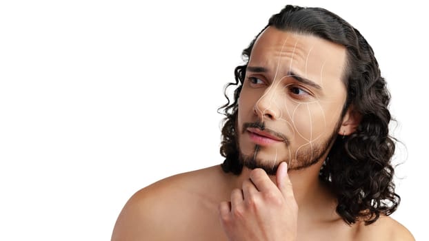 A young man with curly hair and a beard contemplates his skin's appearance, showcasing subtle facial lines and texture under bright lighting in a plain background.