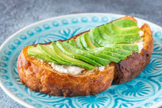 Bright avocado rests on creamy labneh, textures contrast beautifully on toasted bread