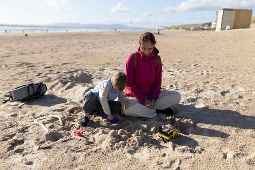 Mother and son enjoying quality time together, building sandcastles on a sunny beach