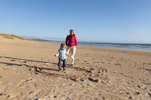 Mother and son enjoying a sunny day playing together on the beach