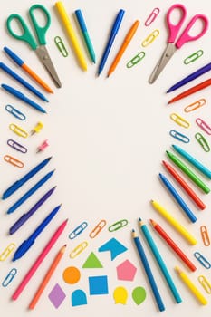 Colorful assortment of school stationery items forming a frame on white background. Includes pens, crayons, paper clips, and scissors. educational content, school marketing, and learning materials.