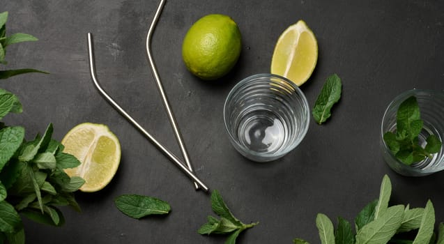 Bunch of fresh green mint, lime slices, glasses and metal straws, top view. Cocktail ingredient